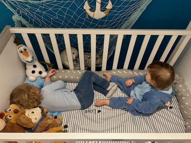Zwei Kleinkinder spielen im Kinderbett